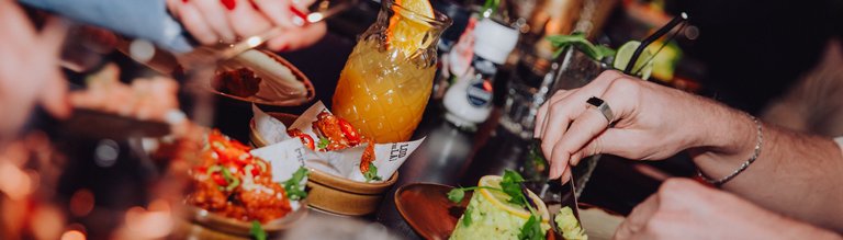 Gezelschap geniet samen van heerlijke gerechten om te delen, kleurrijke cocktails en een gezellige sfeer tijdens een avond uit bij Dekker Zoetermeer.