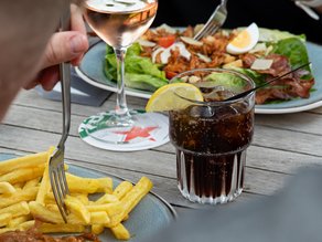 Gasten genieten samen van een gezellige lunch op het terras van Dekker Zoetermeer, met friet, een rijkgevulde salade, rosé en een verfrissend drankje.