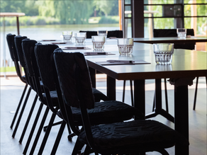Moderne vergaderruimte bij Dekker Zoetermeer met comfortabele zwarte stoelen, een vergadertafel met glazen en notitieblokken en uitzicht op het water en groen.